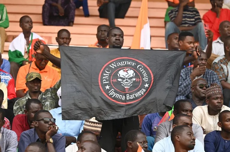 Un nigerian ține un steag cu sigla Grupului Wagner la o manifestație a susținătorilor loviturii de stat din Niger, organizată cu sprijinul mercenarilor Wagner (Niamey, august 2023). Sursa: Foreign Policy/AFP/Getty Images