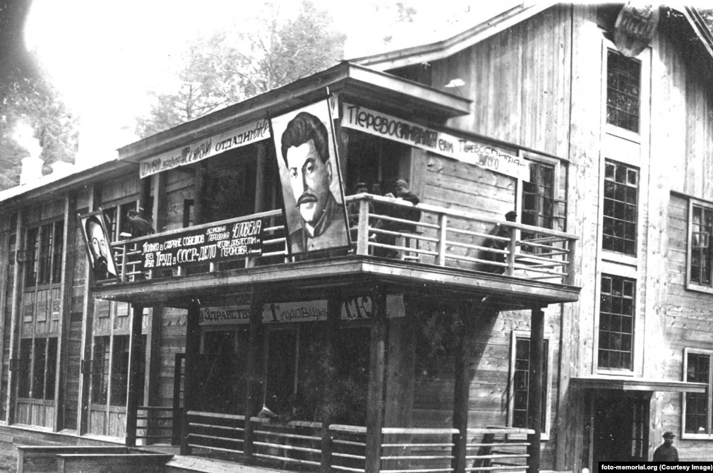Sediul pazei militare din lagărul de muncă de la Tomsk (Siberia) cu lozinca „Numai în țara sovieticilor este posibil să reformezi o persoană prin muncă!” și portretele lui Stalin și Dzerjinski (șeful poliției secrete). Sursa: Radio Europa Liberă